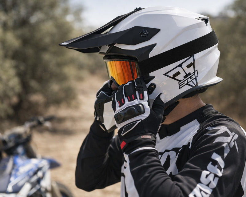 Person wearing a white and black helmet with orange visor, standing in a natural setting.