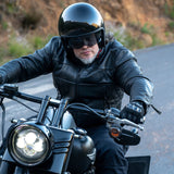 Person riding a motorcycle on a road with a helmet and sunglasses