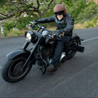 Person riding a motorcycle on a scenic road with greenery