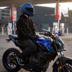 Person on a blue motorcycle at a gas station with 'FUEL' sign.