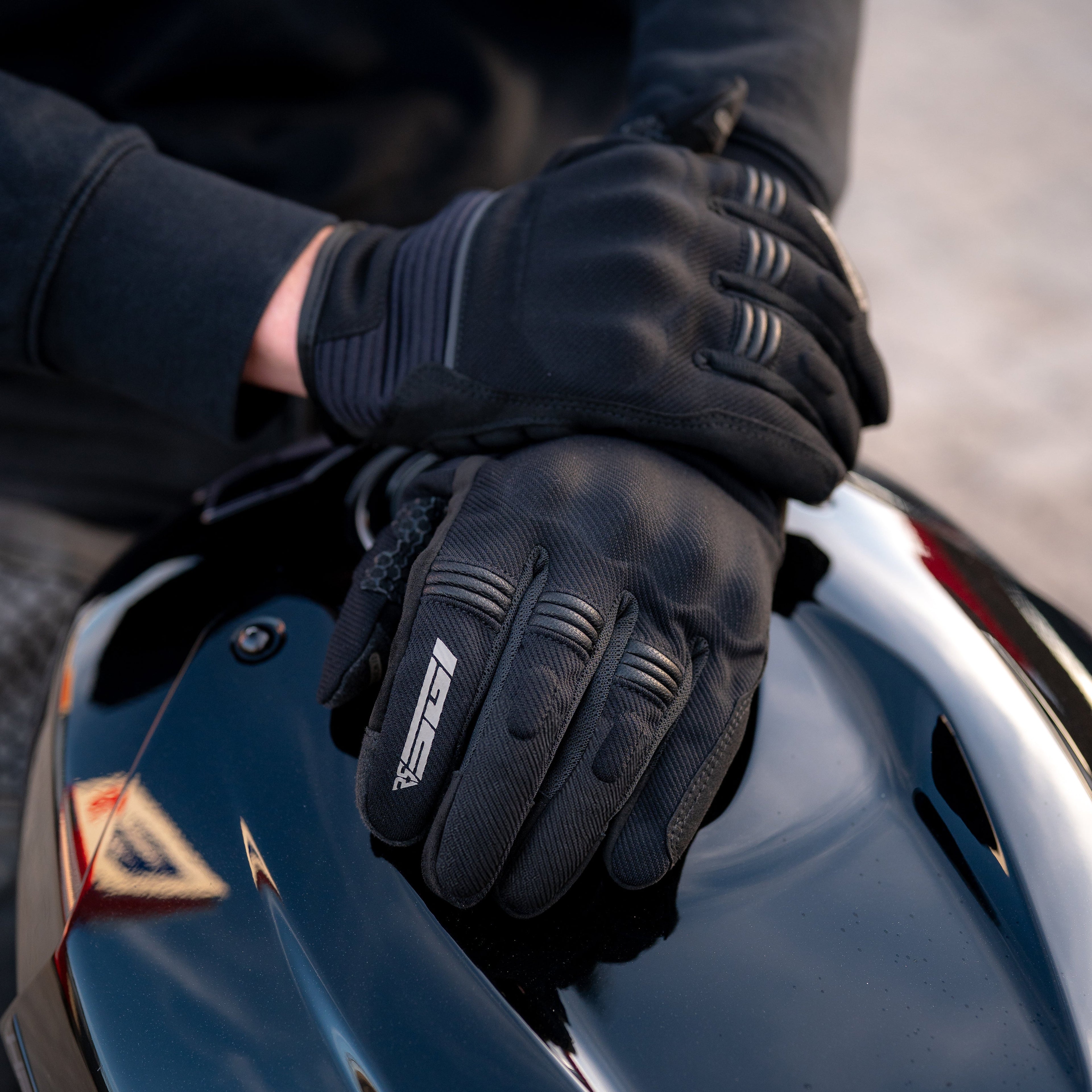 Person wearing black gloves touching a motorcycle helmet