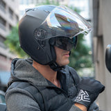 Person wearing a black helmet and gloves, standing outdoors with blurred background
