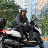 Man riding a scooter in an urban setting with tall buildings in the background