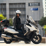 Person sitting on a white and black scooter in an urban setting